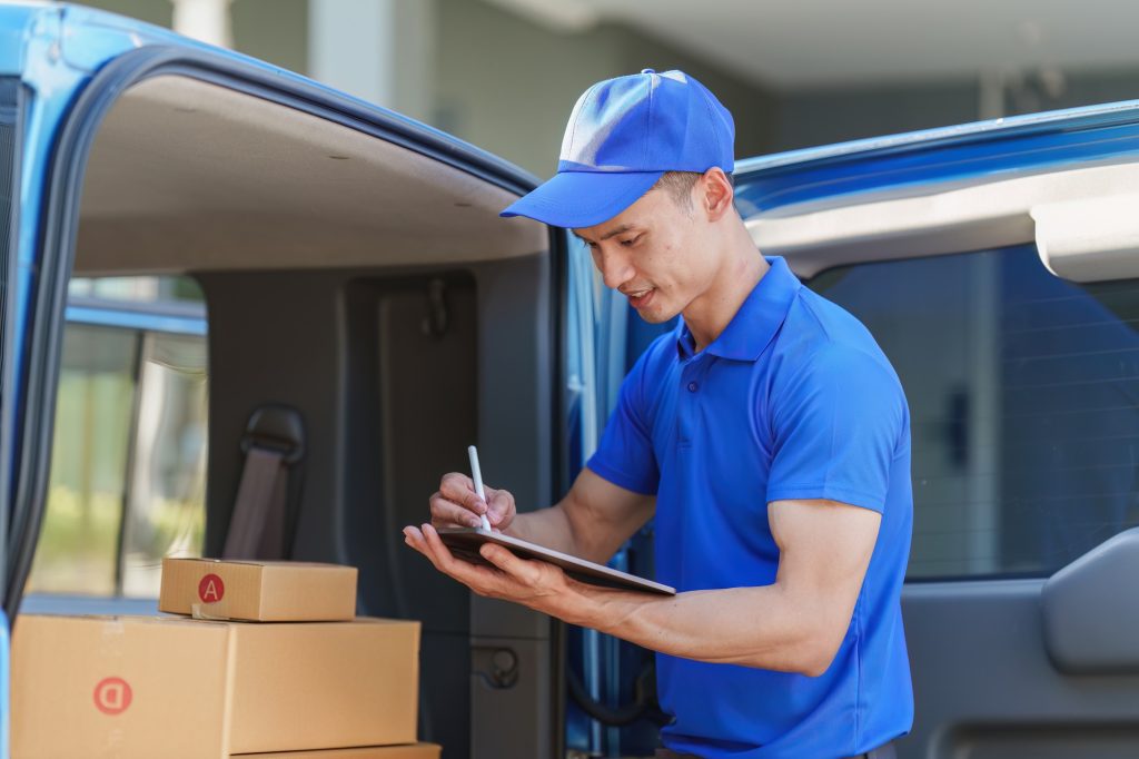 Asian courier with parcel and delivery logistic concept. Delivery man using digital tablet